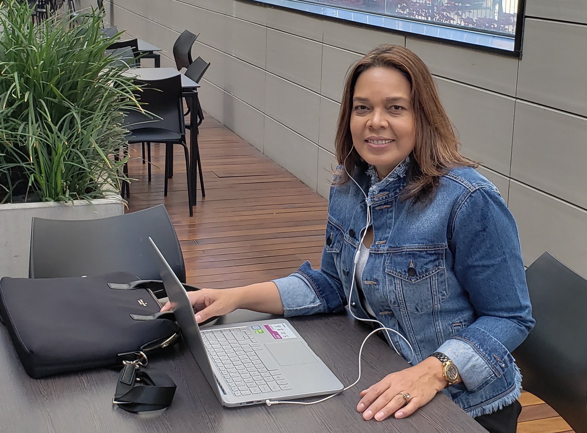 Jo Lima sentada em frente a uma mesa com fone de ouvido